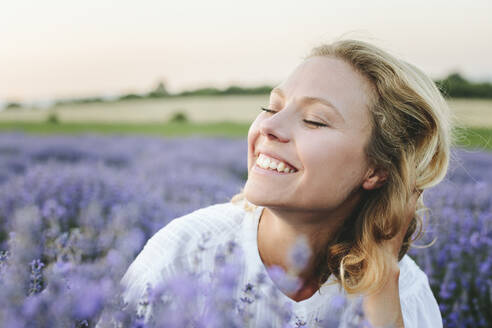 Cheerful woman with blond hair amidst lavender plants - SIF00327