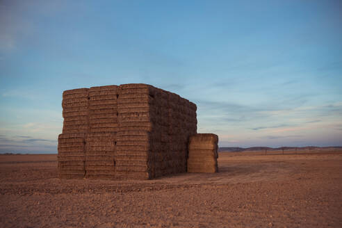Rural landscape with dry hay rolls stacked in field in summer day in countryside - ADSF35675