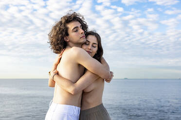 Romantic topless couple embracing by sea - WPEF06126