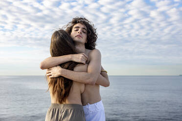 Junge topless Freundin und Freund umarmen einander vor dem Meer - WPEF06127