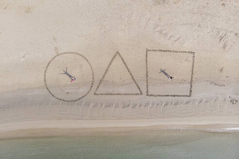 Luftaufnahme von Menschen, die mit Sand am Strand zeichnen, Grosseto, Toskana, Italien. - AAEF15060