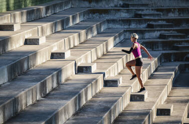 Athletic woman with amputated hand running up steps - TETF01660