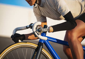 Close-up of athletic woman with prosthetic arm riding bicycle - TETF01662