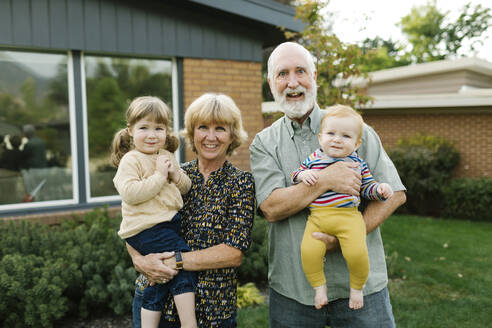Porträt von lächelnden Großeltern mit Enkelkindern (2-3, 4-5) im Hinterhof - TETF01665