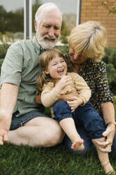 Smiling grandparents with granddaughter (4-5) on back yard - TETF01673