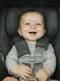 Porträt eines lächelnden Jungen (2-3) im Autositz - TETF01675
