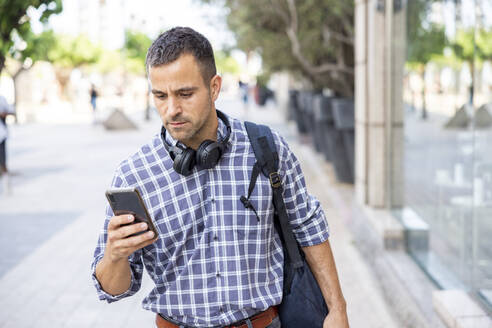 Älterer Mann mit Smartphone auf dem Fußweg - WPEF06148