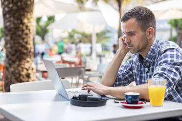 Mature freelancer using laptop sitting at cafe - WPEF06168