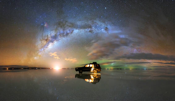 Amazing scenery of SUV car parked on mirrored Salar De Uyuni salt flat reflecting spectacular starry night sky with glowing Milky Way galaxy in Bolivia - ADSF35726