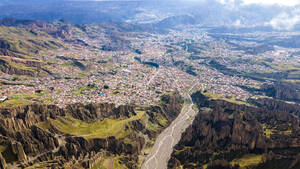 Atemberaubende Luftaufnahme der Stadt in einem Gebirgstal mit malerischen Felsen und zerklüfteten Klippen an einem sonnigen Tag in La Paz - ADSF35730