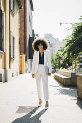 Young businesswoman with laptop standing in city on sunny day - MEUF06868