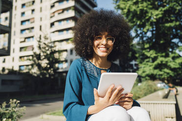 Smiling freelancer with digital tablet on sunny day - MEUF06880