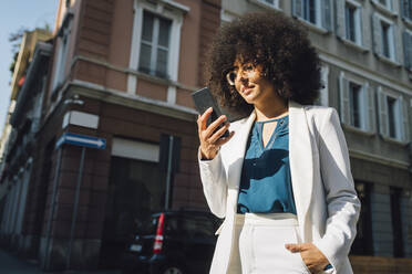 Businesswoman using mobile phone standing in city - MEUF06885