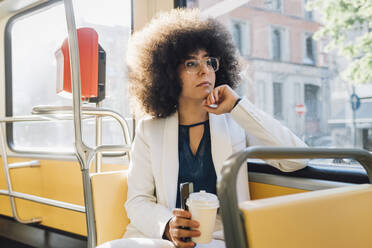 Nachdenkliche schwarze Geschäftsfrau beim Pendeln im Bus - MEUF06900