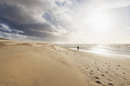 Wolken über Sandstrand bei Sonnenuntergang mit Silhouette von Mann zu Fuß im Hintergrund - GWF07506