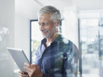 Smiling mature businessman using tablet PC in office - RORF02909