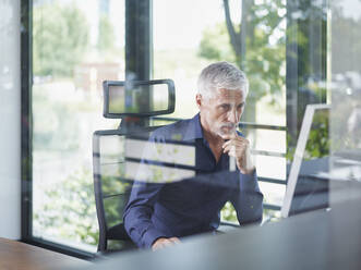 Reifer Geschäftsmann bei der Arbeit an einem Desktop-PC im Büro - RORF02919