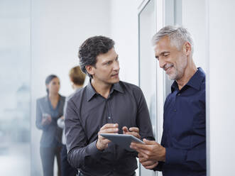 Businessman discussing strategy over tablet PC with smiling mature colleague - RORF02923