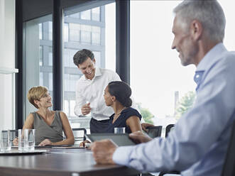 Happy businessman discussing with colleagues in board room - RORF02932