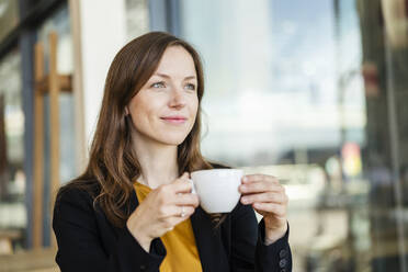 Nachdenkliche Geschäftsfrau mit Tasse in einem Café - DIGF18221