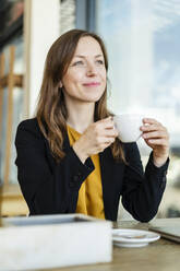 Smiling businesswoman holding cup at cafe - DIGF18222