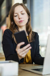 Businesswoman using mobile phone at cafe - DIGF18235