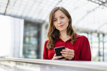 Frau mit braunen Haaren hält Mobiltelefon - DIGF18263