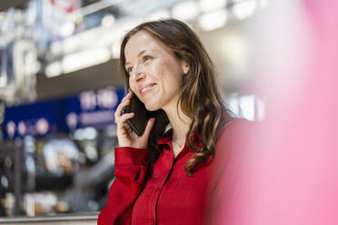 Lächelnde Frau mit braunem Haar, die mit einem Mobiltelefon spricht - DIGF18282