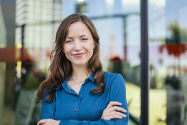 Smiling woman with arms crossed wearing blue shirt - DIGF18299