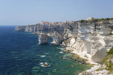 Blick über die felsige Bucht entlang der zerklüfteten Kalksteinklippen auf die entfernte Zitadelle, Bonifacio, Corse-du-Sud, Korsika, Frankreich, Mittelmeer, Europa - RHPLF22415