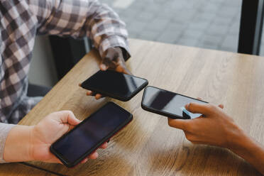 Freunde mit Smartphones am Tisch im Café - OSF00351