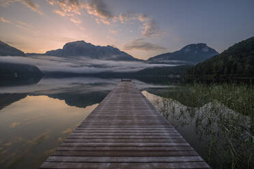 Austria, Styria, Altaussee, Jetty on shore of lake Altaussee at foggy dawn - RUEF03752