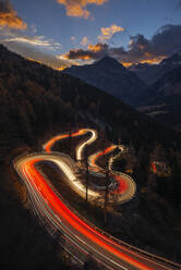 Schweiz, Graubünden, Sankt Moritz, Fahrzeuglichtspuren entlang der Malojapassstrasse in der Abenddämmerung - RUEF03771