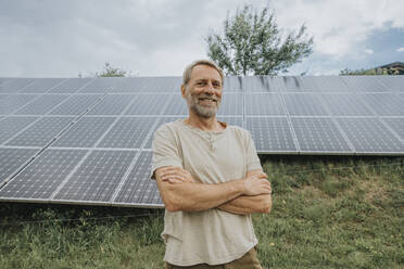 Smiling man with arms crossed in front of solar panels - MFF09278