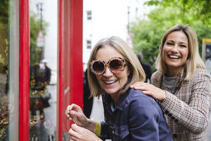 Happy senior woman wearing sunglasses by daughter - ASGF02547