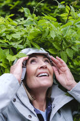 Lächelnde Frau mit Windjacke vor Blättern - ASGF02552