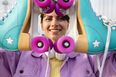 Smiling woman looking through roller skates - VPIF06687