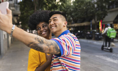 Lächelnder junger Mann nimmt Selfie auf Smartphone mit Frau - JCCMF06667