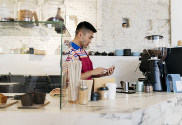 Mann mit Smartphone bei der Arbeit in einem Café - JCCMF06683