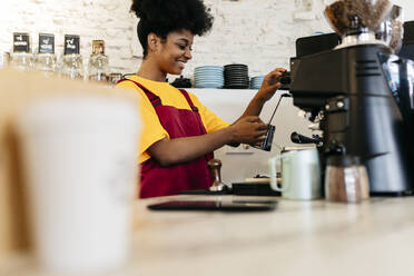 Lächelnde Frau beim Kaffeekochen im Café - JCCMF06688