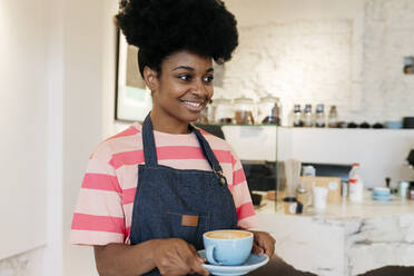 Lächelnde Frau mit Afrofrisur hält Kaffeetasse - JCCMF06706