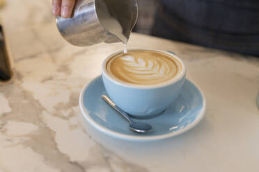 Die Hand des Barista macht Schaum in der Kaffeetasse - JCCMF06736