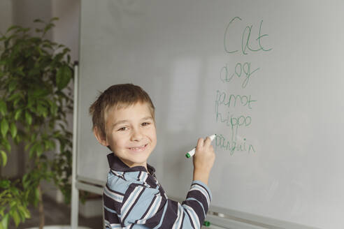 Lächelnder Junge, der zu Hause auf eine Tafel schreibt - OSF00365