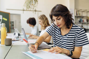 Businesswoman with laptop preparing reports at office - MEUF07063