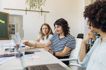 Businesswoman explaining colleagues over laptop in meeting at office - MEUF07071