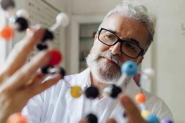 Scientist wearing eyeglasses looking at molecular structure - MEUF07181