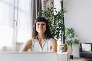 Smiling woman working on laptop at home - MEUF07205