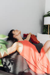 Woman with arms outstretched relaxing on sofa at home - MEUF07256