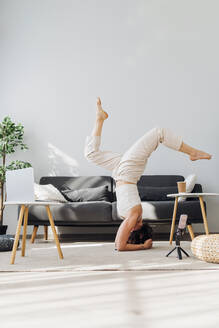 Frau übt Yoga am Laptop zu Hause - MEUF07270