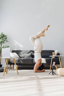 Frau übt Yoga mit Laptop zu Hause - MEUF07271